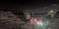 A wide shot of an outdoor stadium concert at night.
