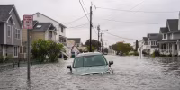 A car is seen submerged in water on a flooded road.