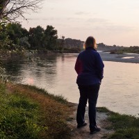 Overweight Woman Standing on a Riverbank at Sunrise