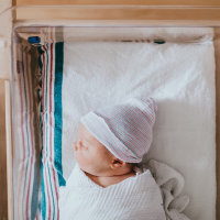 Newborn Baby Sleeping In Hospital Bassinet