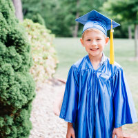 Portrait of happy boy in graduation gown standing at park