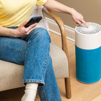 Woman pressing the button on a Blue Air Purifier