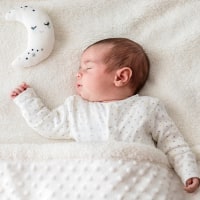 Baby boy in bed sleeping with moon