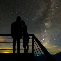 A couple standing on the balcony on the scenic starry sky background.