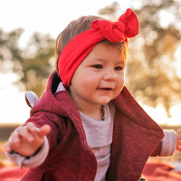 Portrait of a cute baby girl sitting on a picnic blanket outdoors.