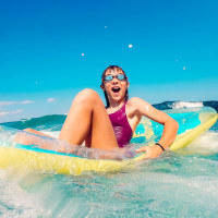Girl having fun on the beach floating on airbed