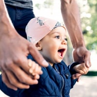 Midsection of father walking with toddler at park