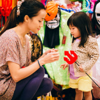 Pretty young mom and lovely toddler girl shopping for Halloween costume accessories in the department store.