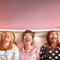 Girls wearing cucumber slices on eyes in bed