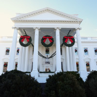 The White House with three large christmas wreaths hanging between the columns.