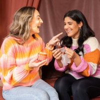 two women who are sisters, laughing while applying skincare products
