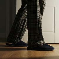 Man in a pajamas and slippers walks to a toilet at home in the night.