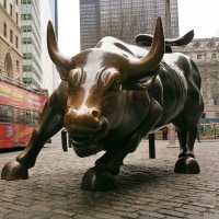 A tour bus passes the Wall Street bull in the financial district in NYC.