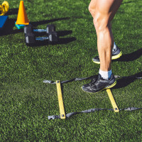 Man legs training with agility ladder and cones on the side