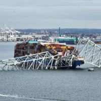 The steel frame of the collapsed Francis Scott Key Bridge sits on top of a container ship, in Baltimore