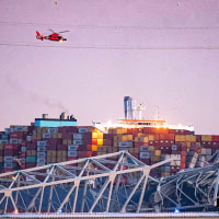 A US Coast Guard helicopter flies over the Dali container vessel after it struck the Francis Scott Key Bridge