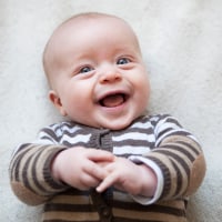 Portrait of laughing baby boy lying on blanket