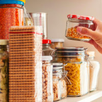 a man placing glass jars in organized pantry