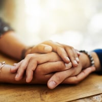 Closeup shot of two people holding hands in comfort
