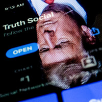 This photo illustration shows an image of former President Donald Trump reflected on a phone screen that is displaying the Truth Social app