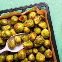 Homemade roasted brussels sprouts in tray on green table.