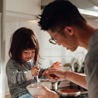 Young Asian father and daughter cooking together in kitchen at home