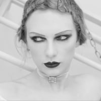 Swift with her hair in pincurls, thin eyebrows, dark lipstick is chained to a bed.