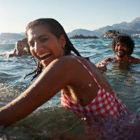 Happy young woman holding hand of boyfriend while enjoying swim in sea on sunny day