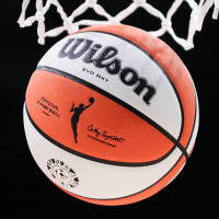 A detail of the WNBA logo is seen on a basketball falling through a hoop