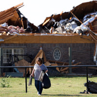 A women removes items from a home with storm damage.