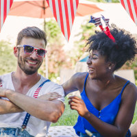 friends in backyard on picnic blanket with American flags.