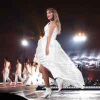 Taylor Swift in white dress on stage at Eras Tour.