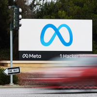 A red car drives by the Meta sign at the company's headquarters in Menlo Park