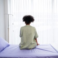 Black woman patient sitting on the hospital bed.