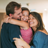 Parents and daughter cuddling in the living room.