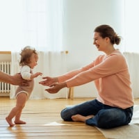 Parents helping daughter walking at home.