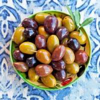 Assortment of fresh olives on a plate. Blue background.