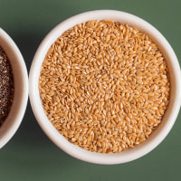 Top view of whole chia and flax seeds in small round white ceramic bowls, side by side, on a studio background with copy space.