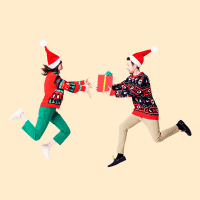 Man and woman in Santa hats and Christmas sweaters giving presents in mid air against cream background.
