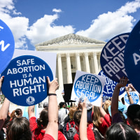 People hold signs saying "Safe Abortion is a Human Right" and "Keep abortion legal"