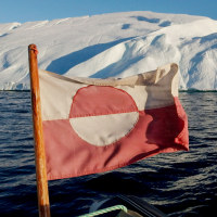 Greenland's flag flutters on a tourist boat as it sails past icebergs