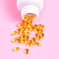Supplements in a white bowl on pink background.