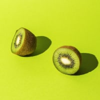 Sliced fruit of fresh kiwi on a bright green background.