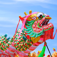 Two colorful Chinese dragon dance performances against blue sky background during Chinese New Year celebrate festival