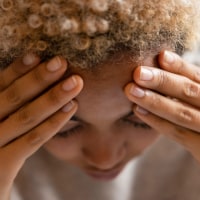 Woman with headache rubbing forehead.