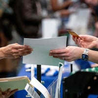 An attendee hands a resume to a recruiter at a job fair hiring event in Sacramento, Calif., on Feb. 27, 2025. 