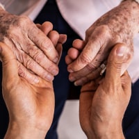 Close-up of a caregiver holding hands senior woman patient