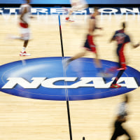 Players dribble the ball on the NCAA logo at half court