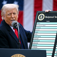 Donald Trump speaks into a microphone at a podium and holds a sign titled "reciprocal tariffs" with a list of countries and percentages