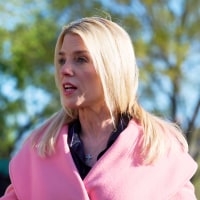 Pam Bondi gestures while she speaks with reporters.
